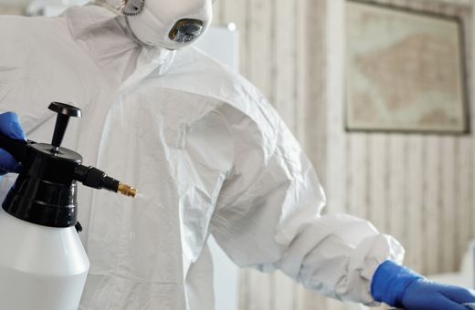 Worker in a protective suit cleaning indoor surfaces