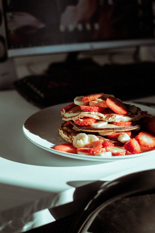 Free Pancakes With Slices Of Banana And Strawberry on White Ceramic Plate Stock Photo