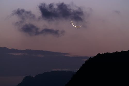 雲に覆われた月の下の山のシルエット