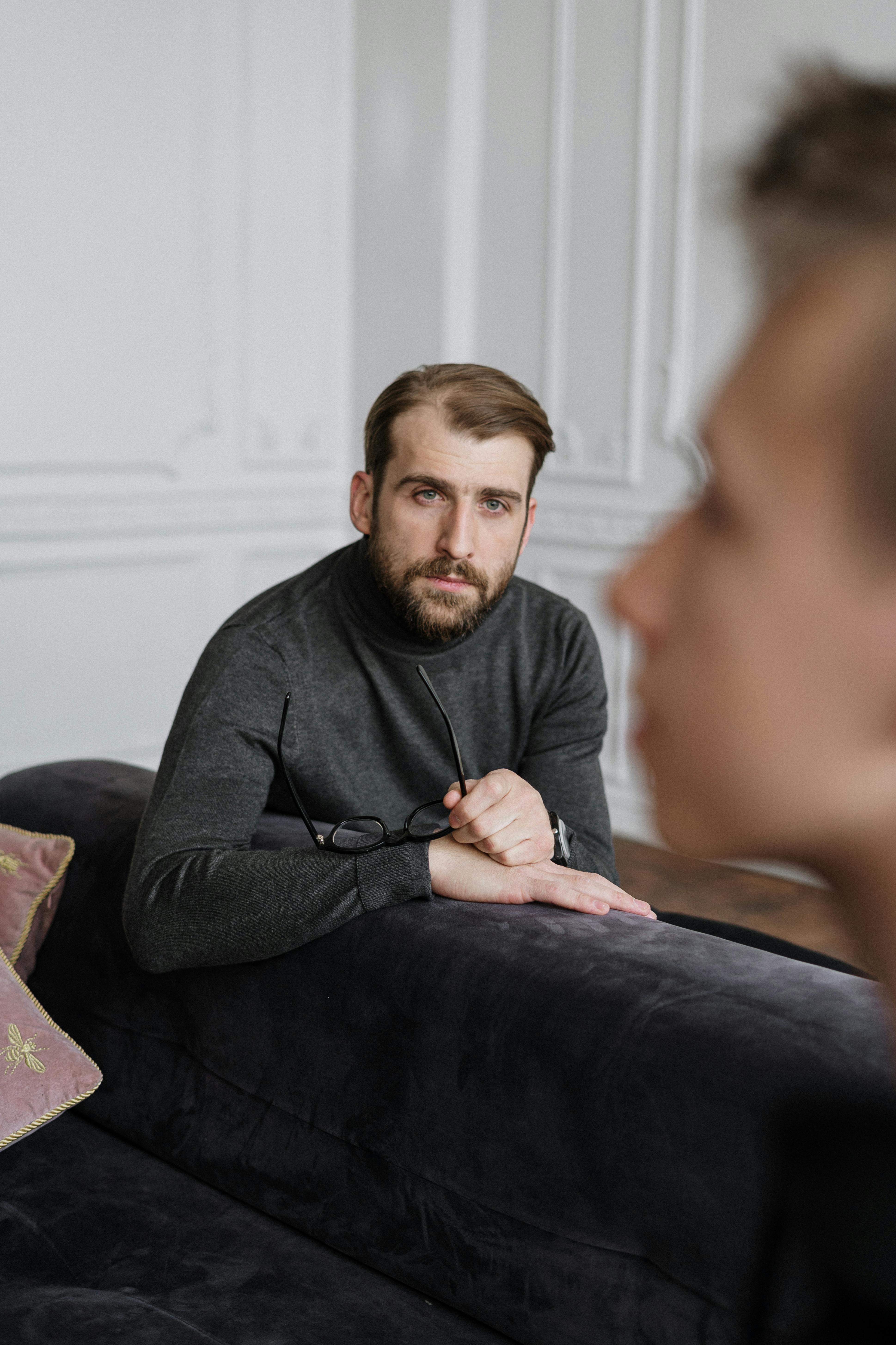 man in gray sweater sitting on purple couch