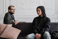 在现代办公室环境中，一名治疗师正与一名十几岁的男孩讨论心理健康问题