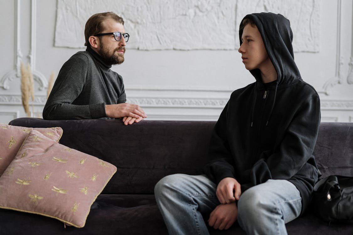 Man in Black Jacket Sitting on Brown Couch