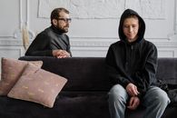 一名青少年穿着黑色连帽衫，在安静的室内接受治疗