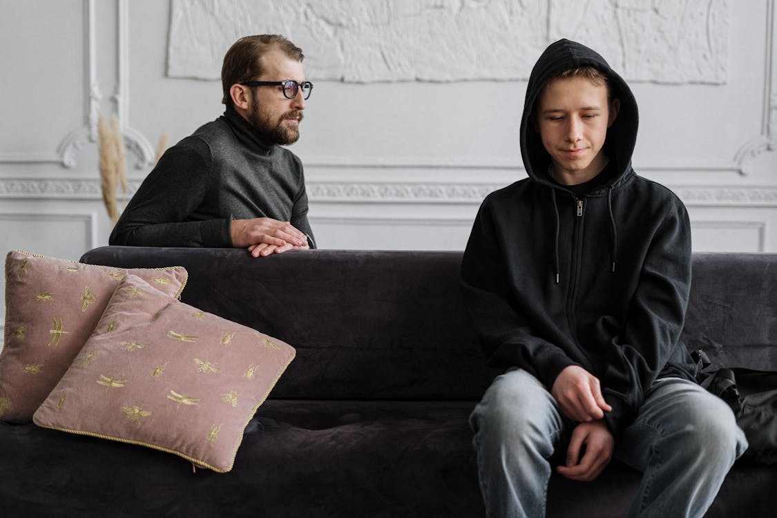 Free Man in Black Hoodie Sitting on Brown Couch Stock Photo