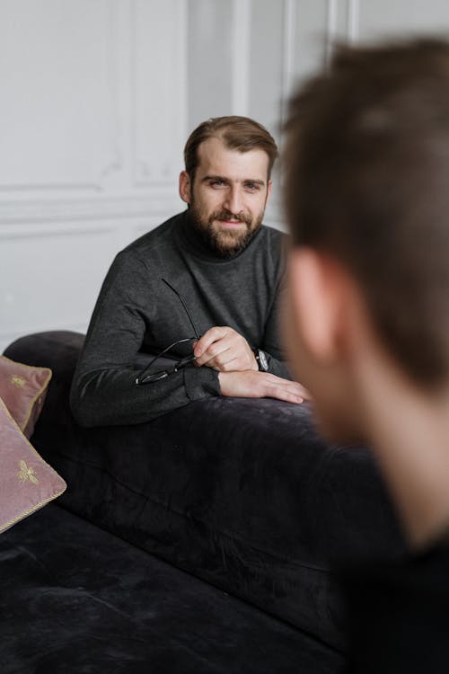 Man in Black Crew Neck T-shirt Sitting on Black Sofa