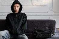 一个穿着连帽衫的年轻人若有所思地坐在沙发上
