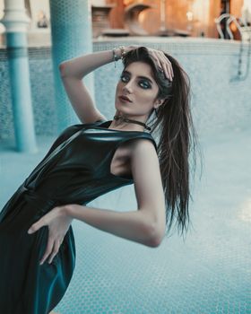 Stylish woman in a sleek dress posing elegantly in a contemporary setting.