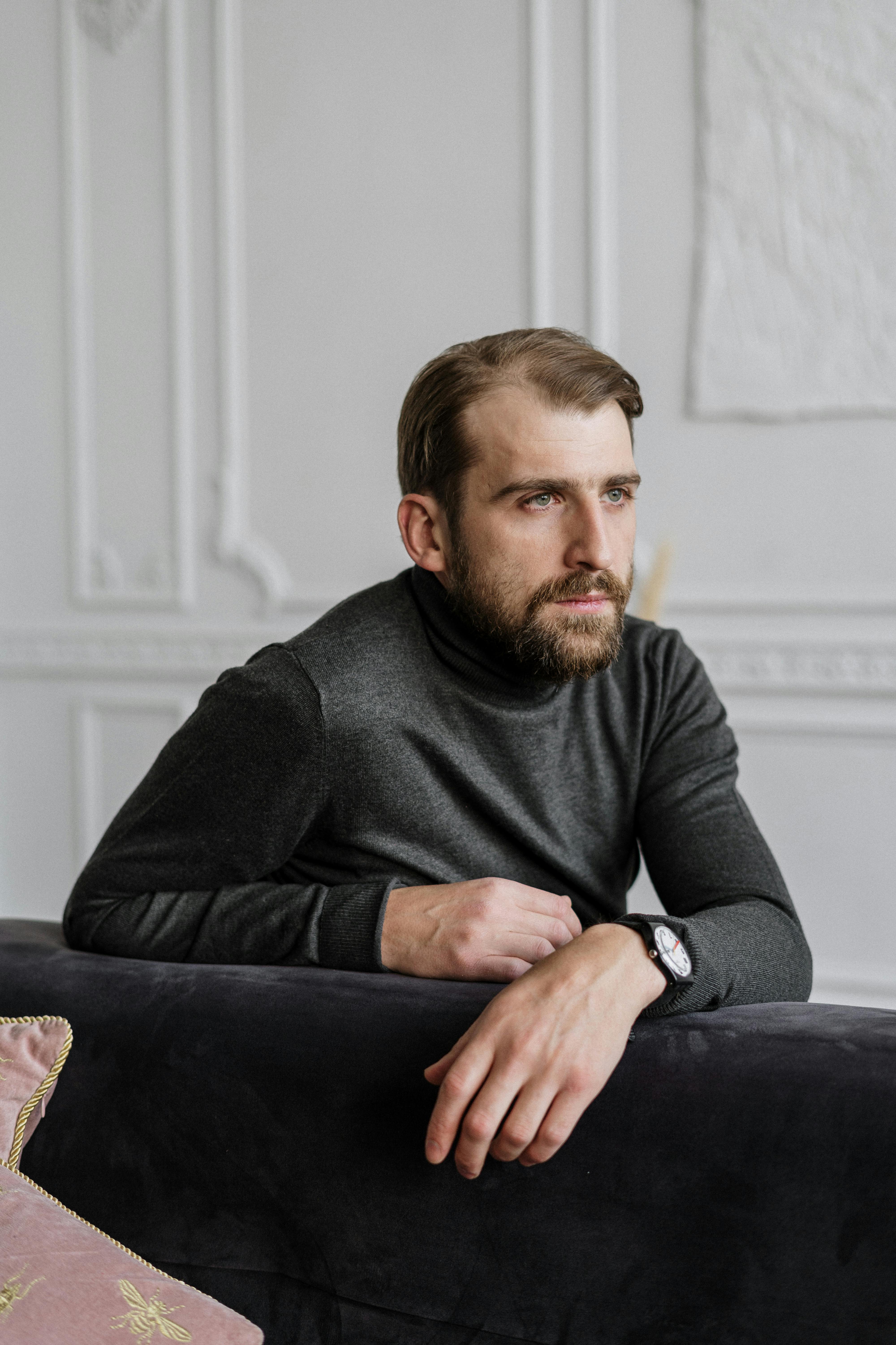 man in black sweater sitting on black couch