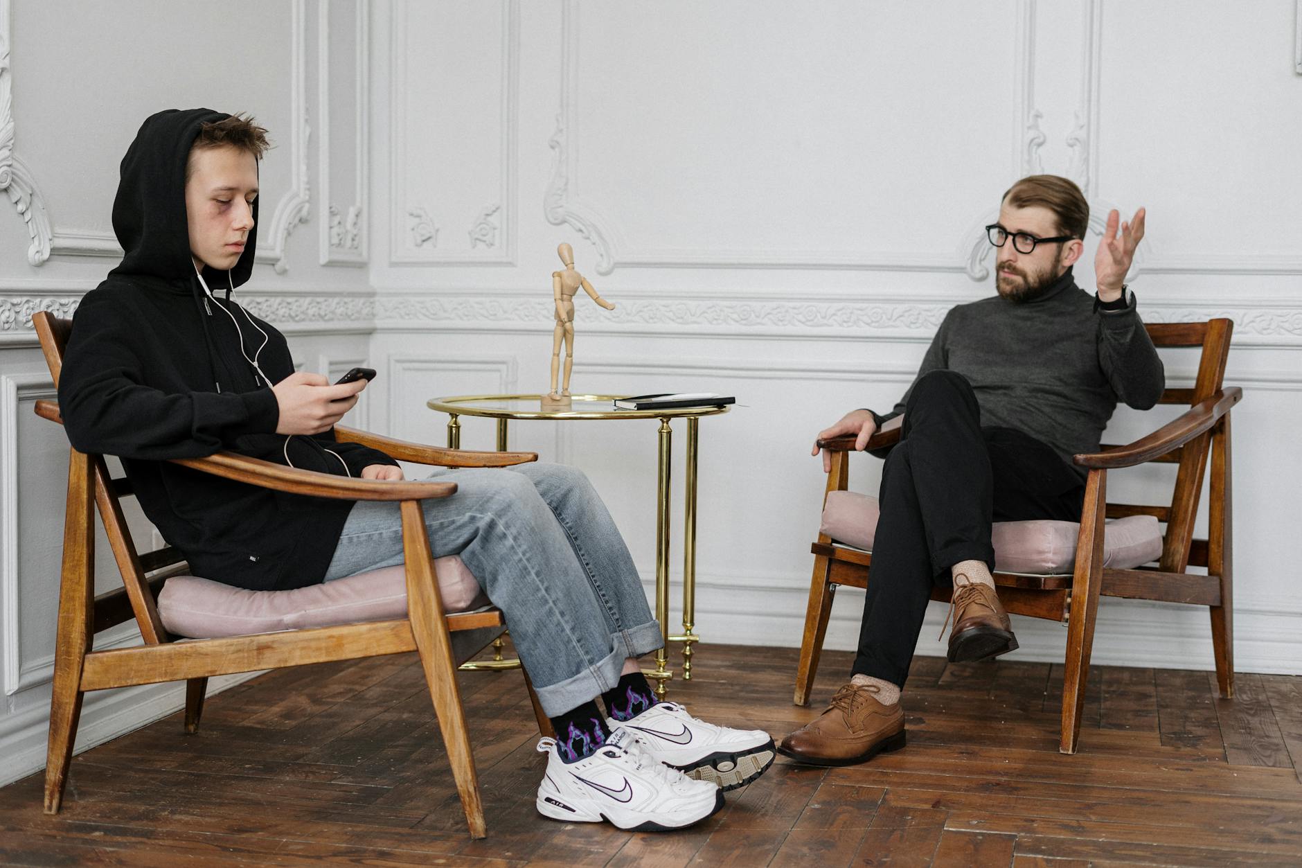 Man in Black Sweater and Blue Denim Jeans Sitting on Brown Wooden Rocking Chair