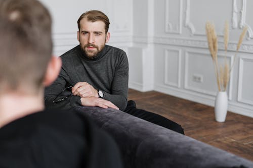 Man in Gray Sweater Sitting on Black Couch