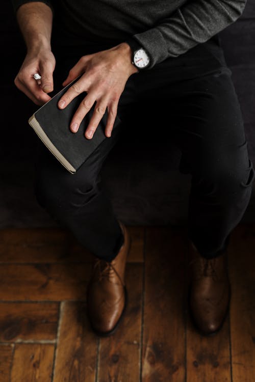 Free Person in Black Pants and Brown Shoes Sitting on Black Chair Stock Photo