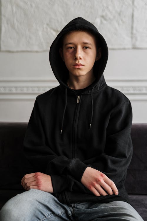 Man in Black Hoodie Sitting on Black Couch