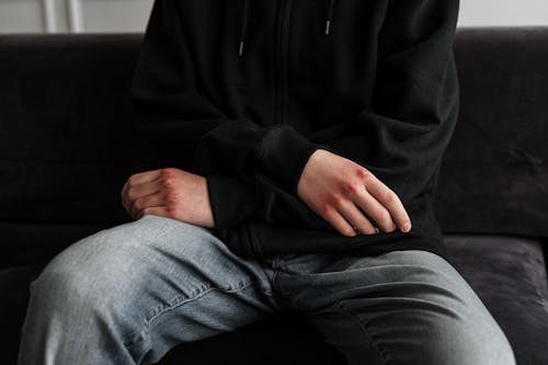 Free Person in Black Jacket and Blue Denim Jeans Sitting on Black Couch Stock Photo