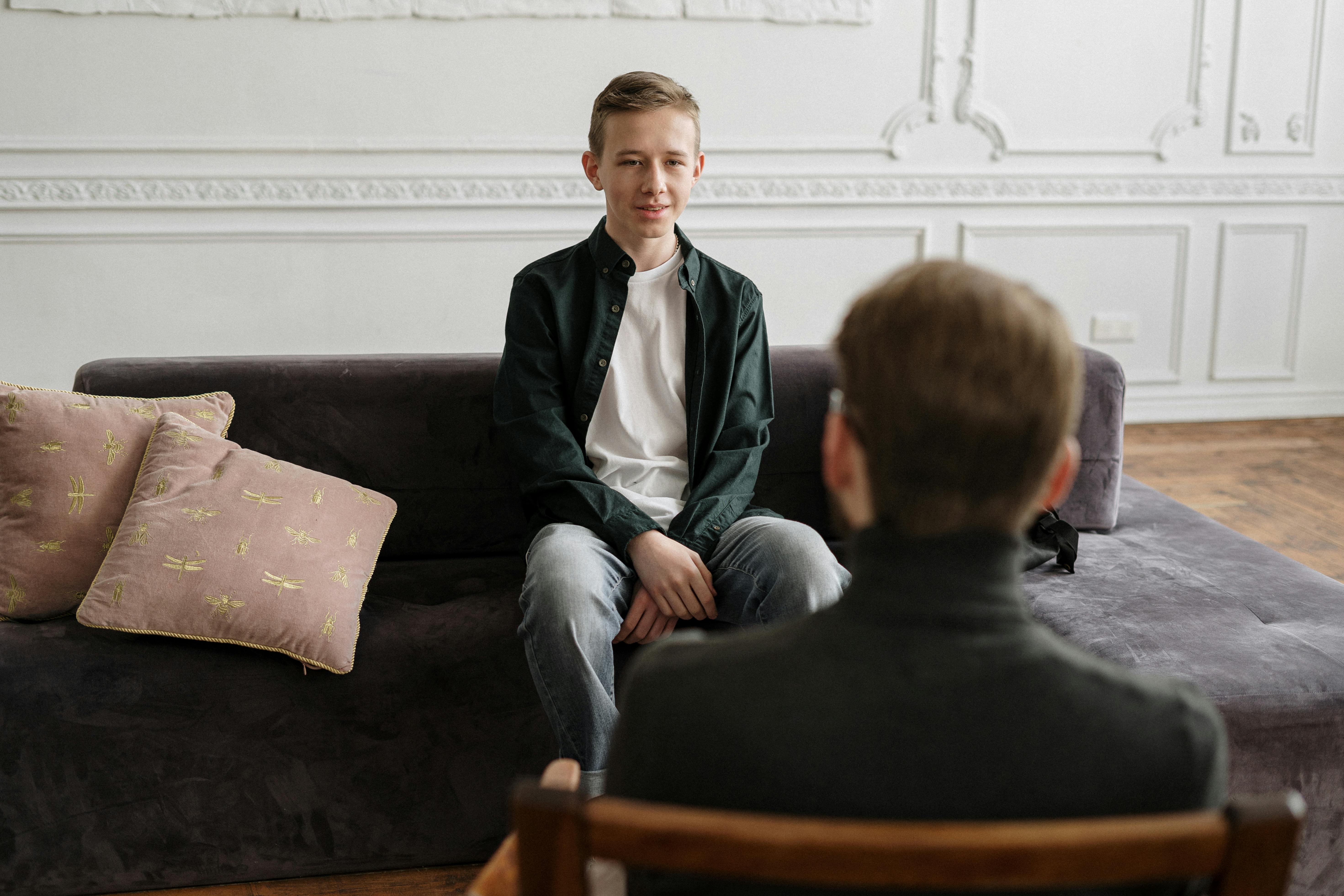 man in black suit sitting on brown couch