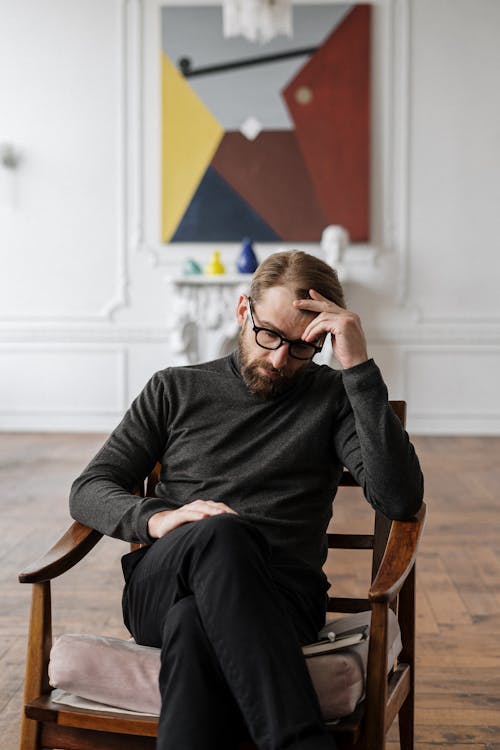 Free Man in Black Sweater Sitting on Brown Wooden Chair Stock Photo