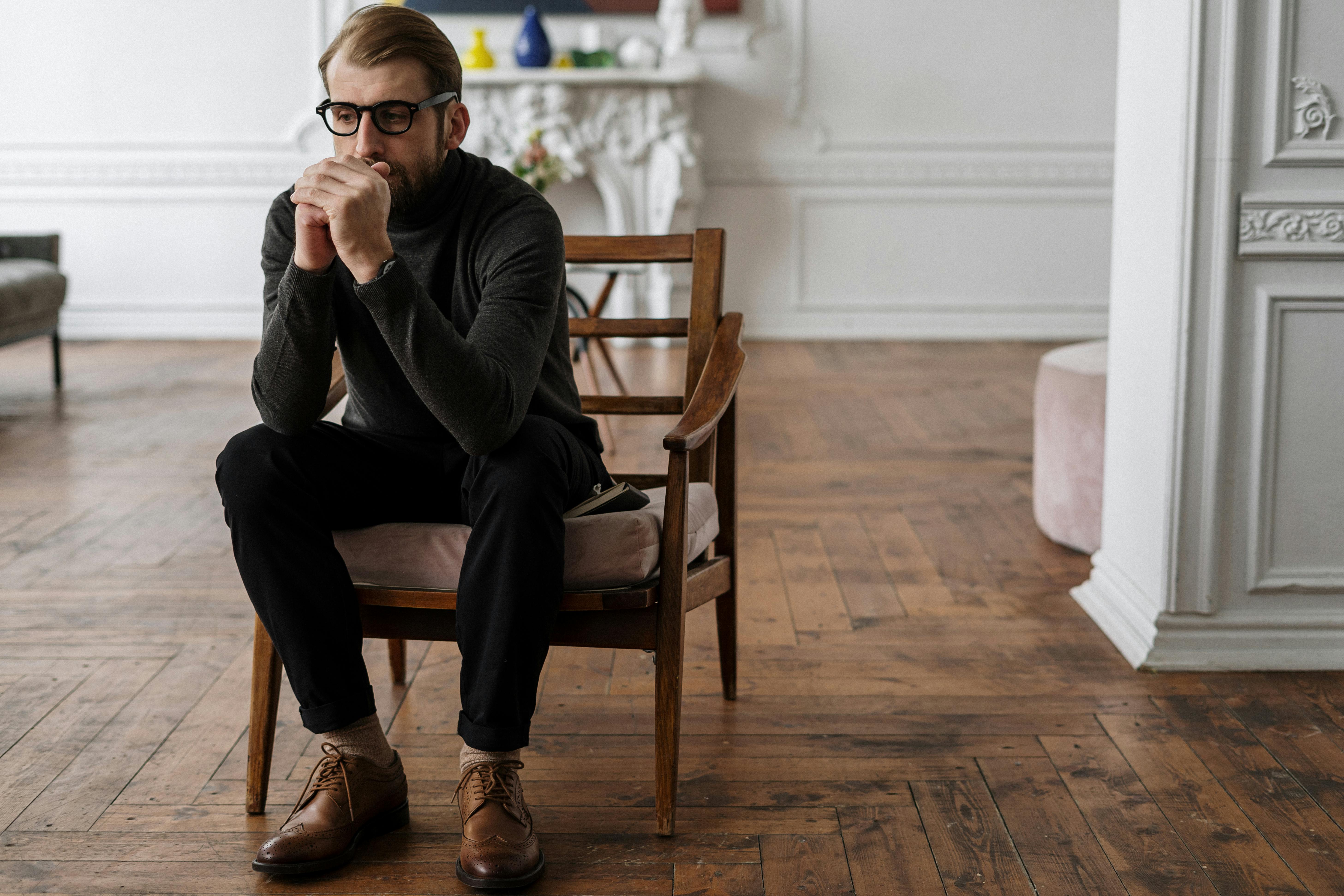 woman in black long sleeve shirt and black pants sitting on brown wooden armchair