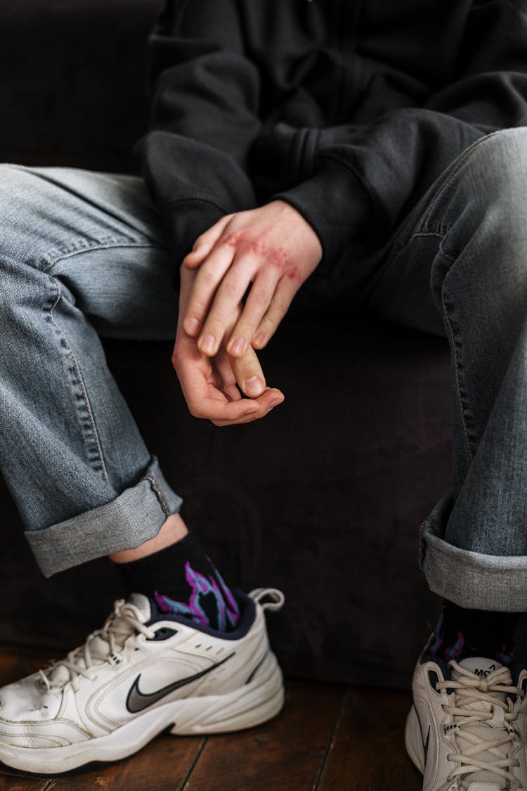 Person In Blue Denim Jeans And Purple And White Nike Sneakers