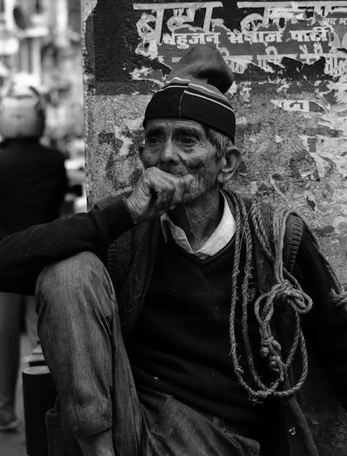 Ethnic old man sitting next to shabby wall