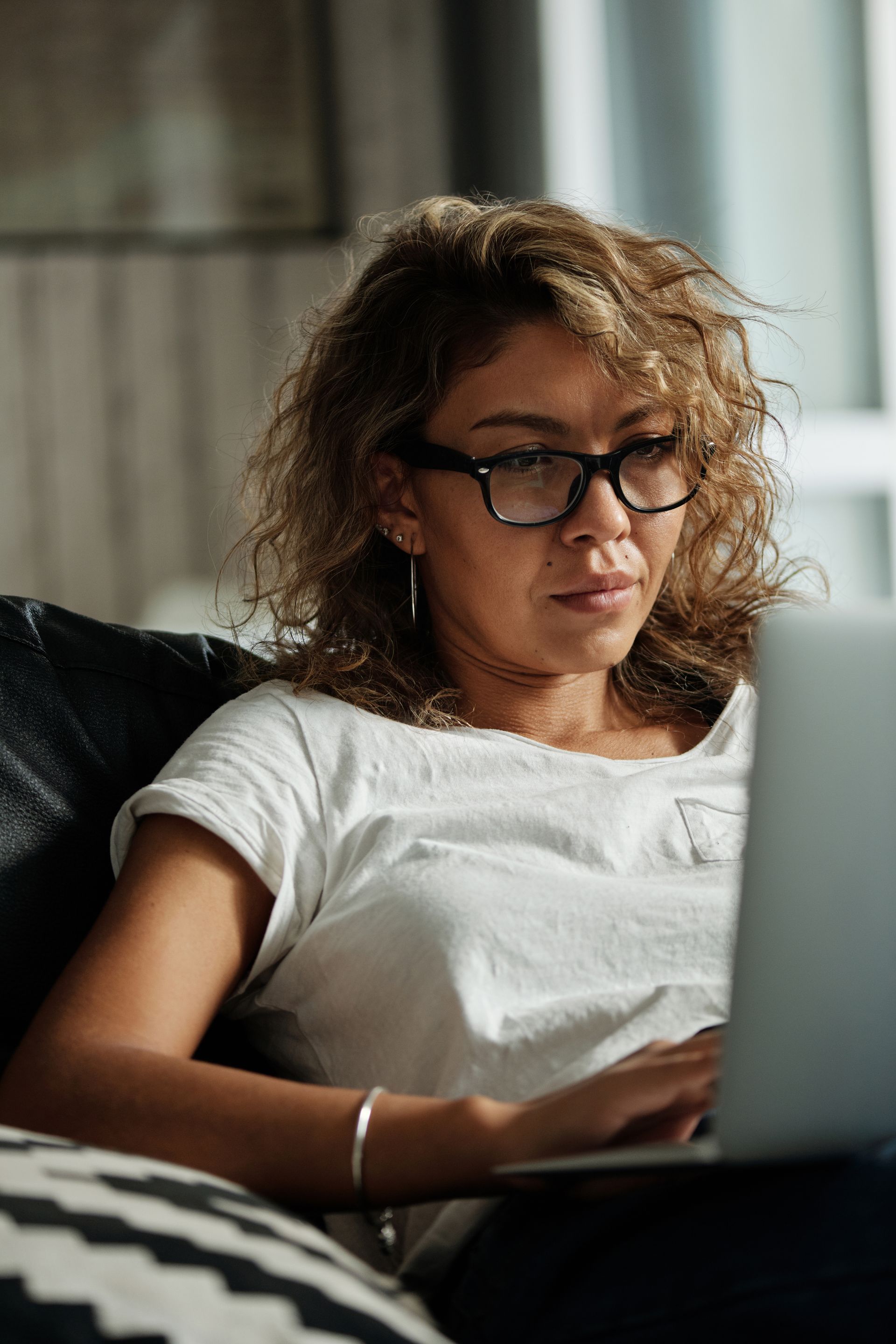 A parent relaxed on a sofa, looking at a laptop