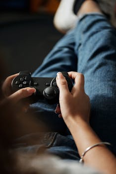 Focused shot of hands with a game controller, person lounging in denim.