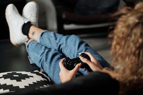 Free Person in Blue Denim Jeans Holding Black Sony Ps 4 Controller Stock Photo