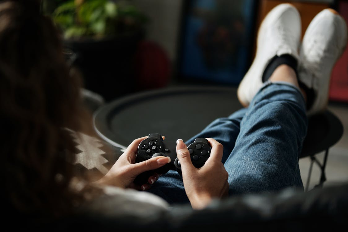 Free Person in Blue Denim Jeans Holding Black Game Controller Stock Photo