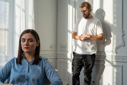 Free Man in Blue Polo Shirt and Black Pants Standing Beside Woman in White Long Sleeve Shirt Stock Photo