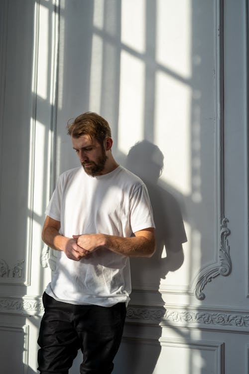 Free Man in White Crew Neck T-shirt Standing Beside Window Stock Photo