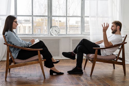 Free Person in Black Pants and Black Shoes Sitting on Brown Wooden Chair Stock Photo