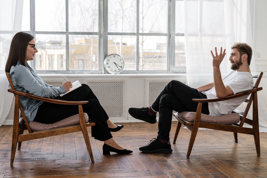 Person in Black Pants and Black Shoes Sitting on Brown Wooden Chair to talk about task delegation anxiety