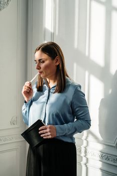 阳光明媚的房间里，一个女人拿着笔记本，象征着反思和沉思