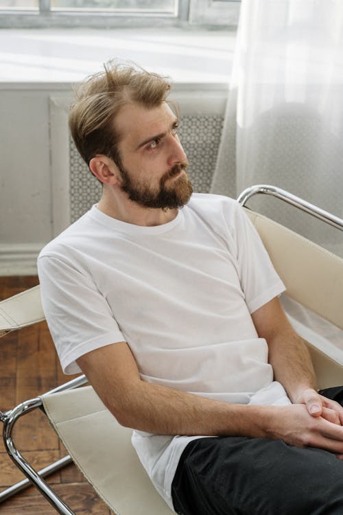 Man in White Crew Neck T-shirt Sitting on White Chair