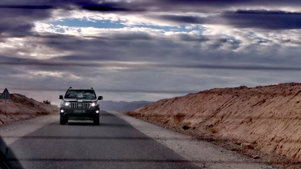 A person writing goals in a notebook with a glass of water beside them