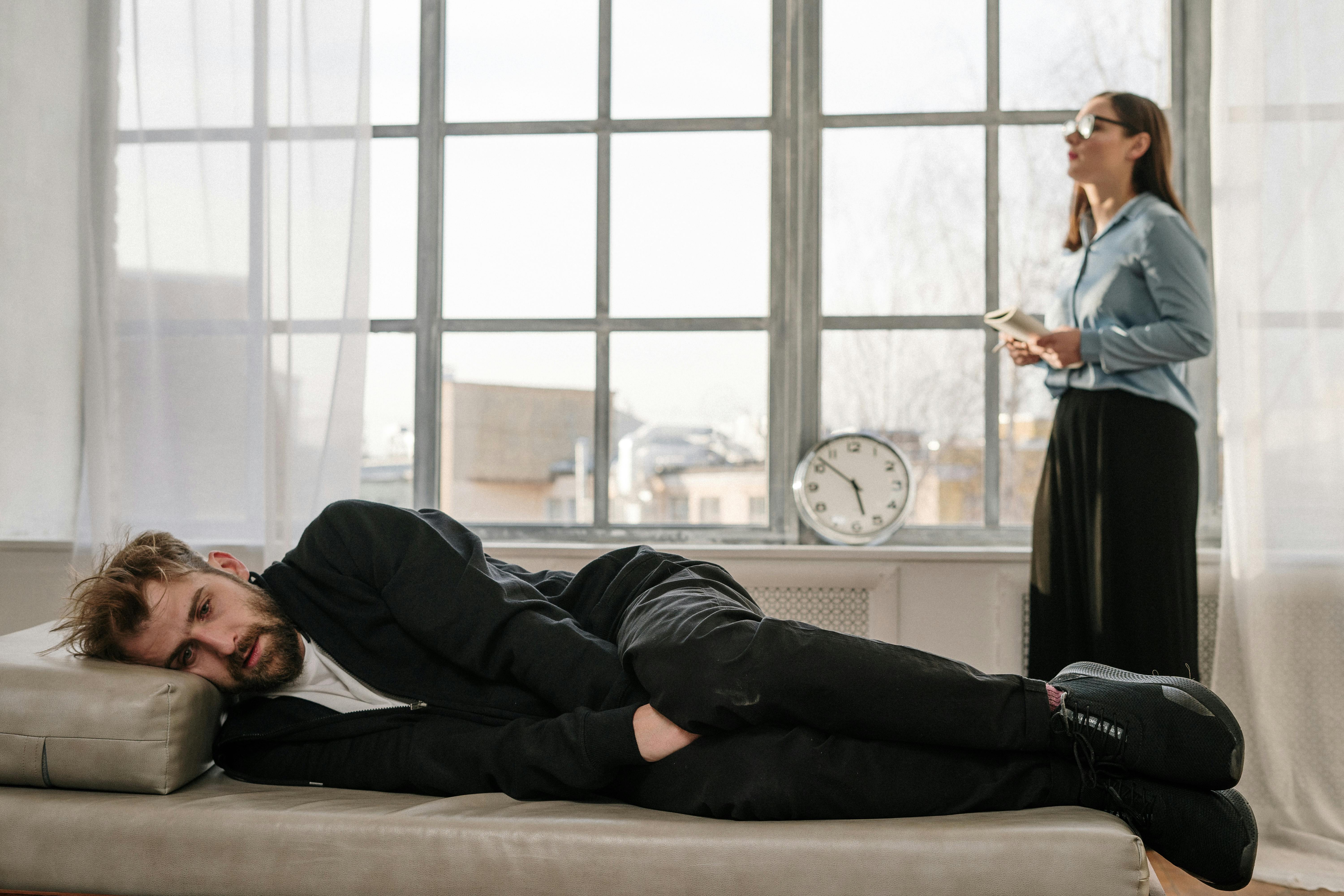 man in black long sleeve shirt lying on brown couch