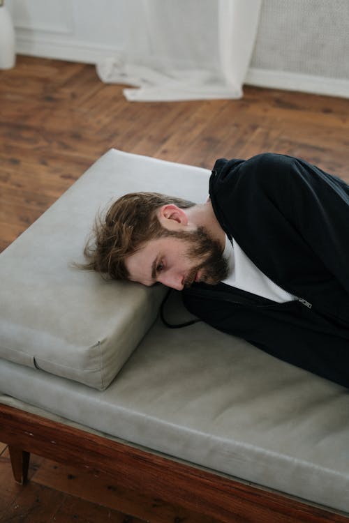 Man in Black Long Sleeve Shirt Lying on Gray Couch