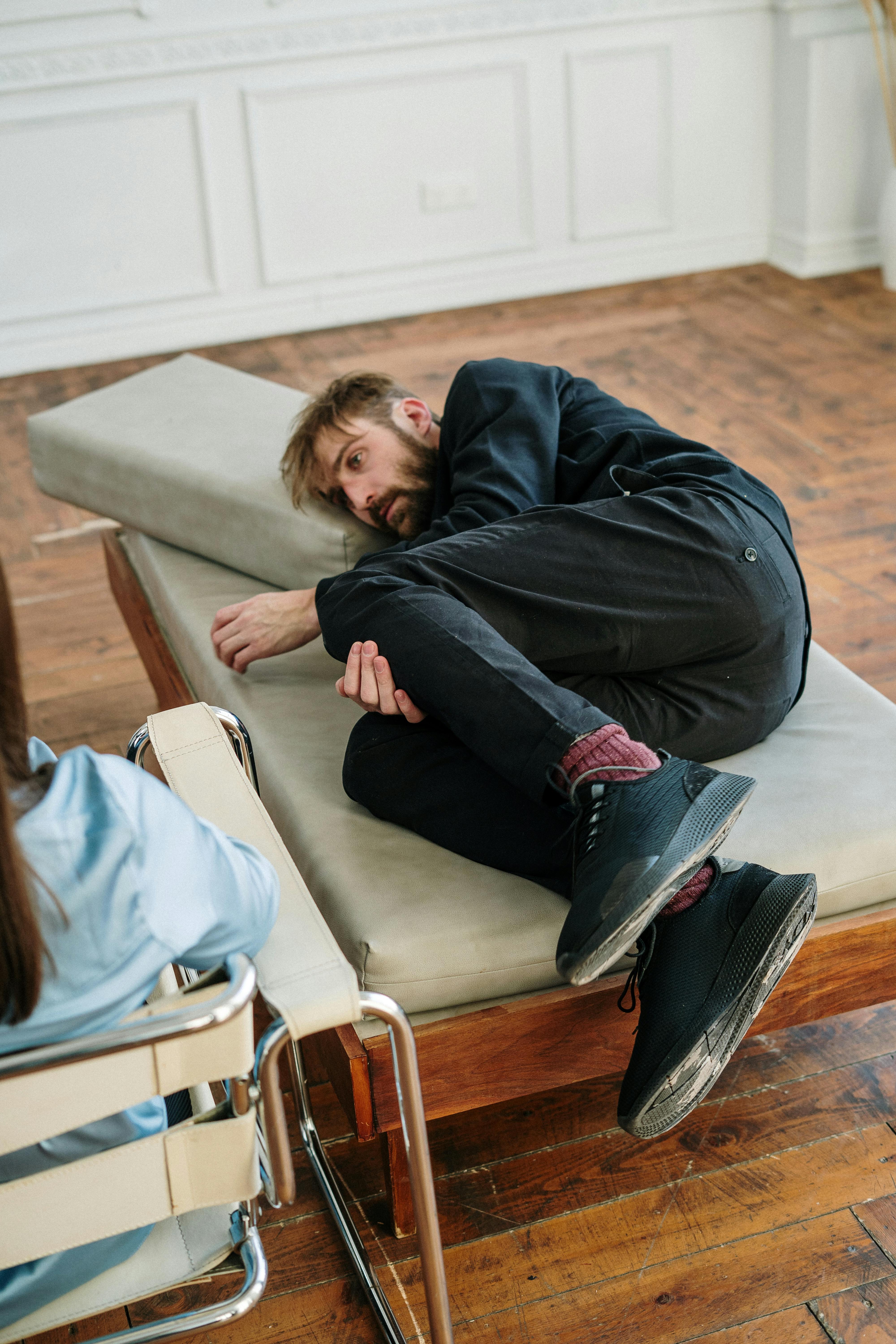 man in black long sleeve shirt lying on gray couch