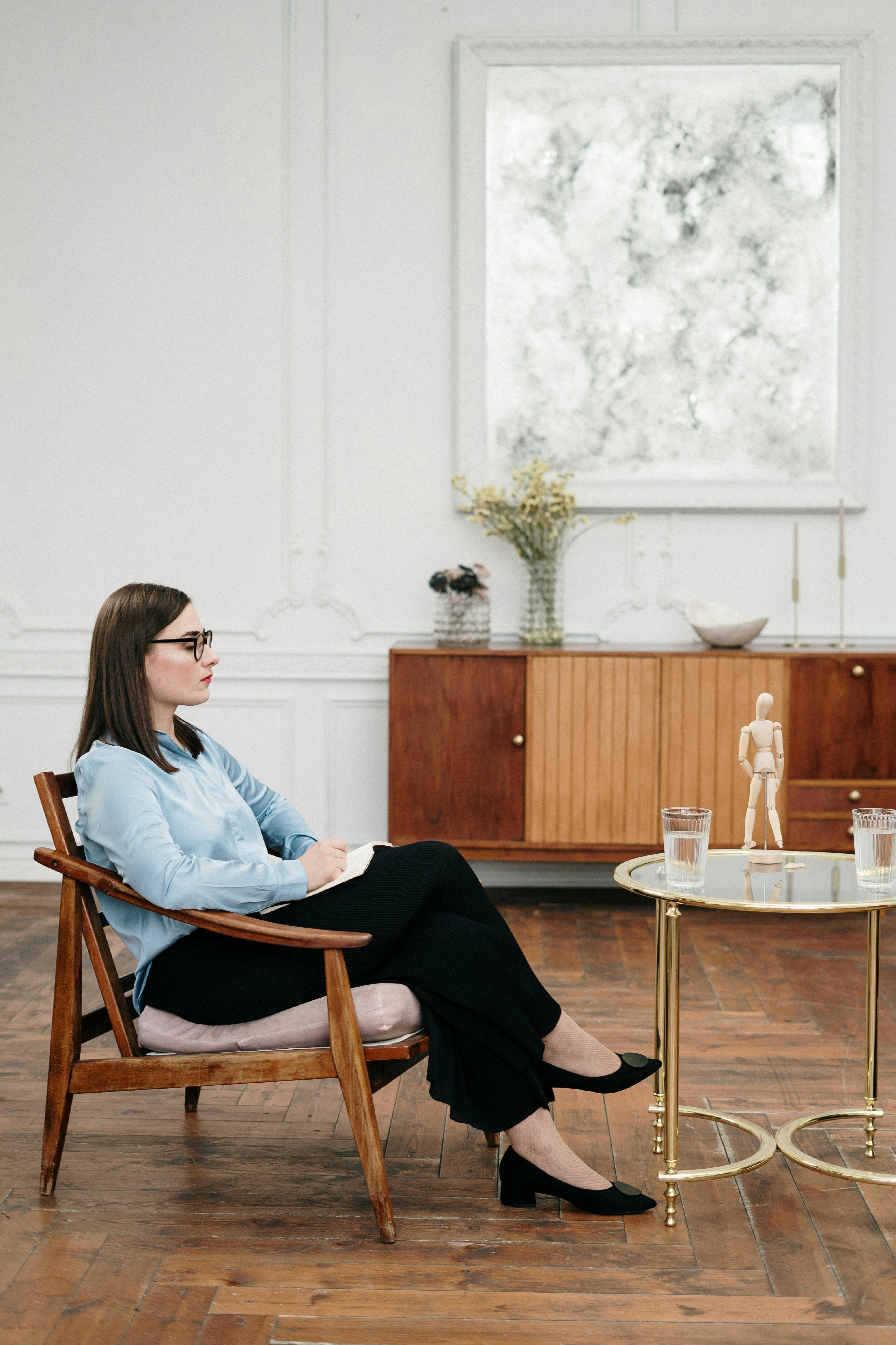 woman in blue dress shirt sitting on brown wooden chair