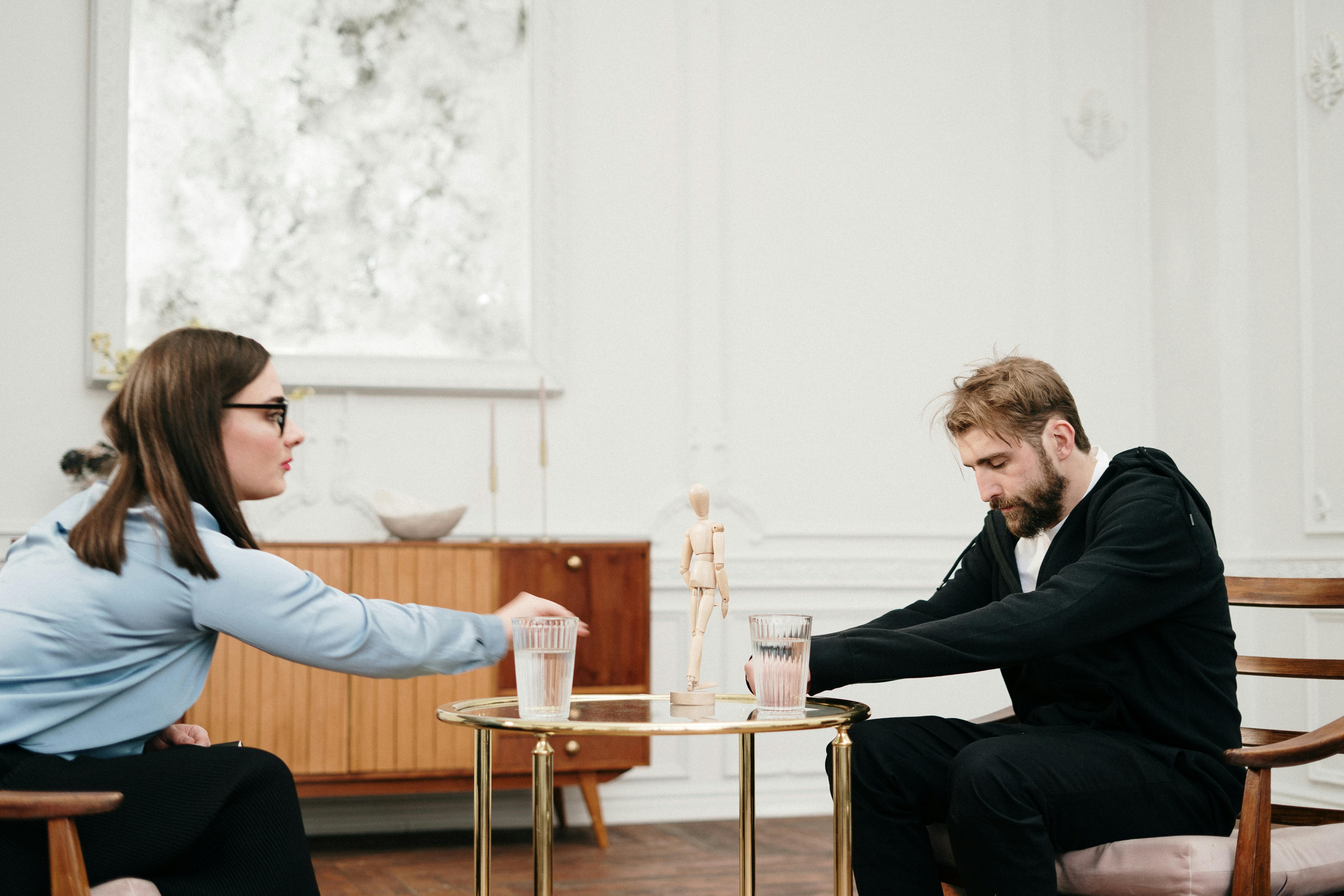 man in black suit sitting on chair in front of man in black suit