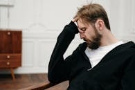 一名男子若有所思地坐着，手托着脸，捕捉到内省与压力的瞬间