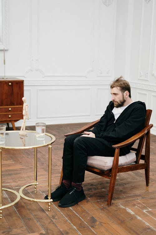 Man in Black Suit Sitting on Brown Wooden Chair