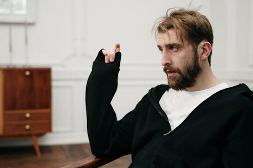 Man in Black Sweater Sitting on Brown Wooden Chair