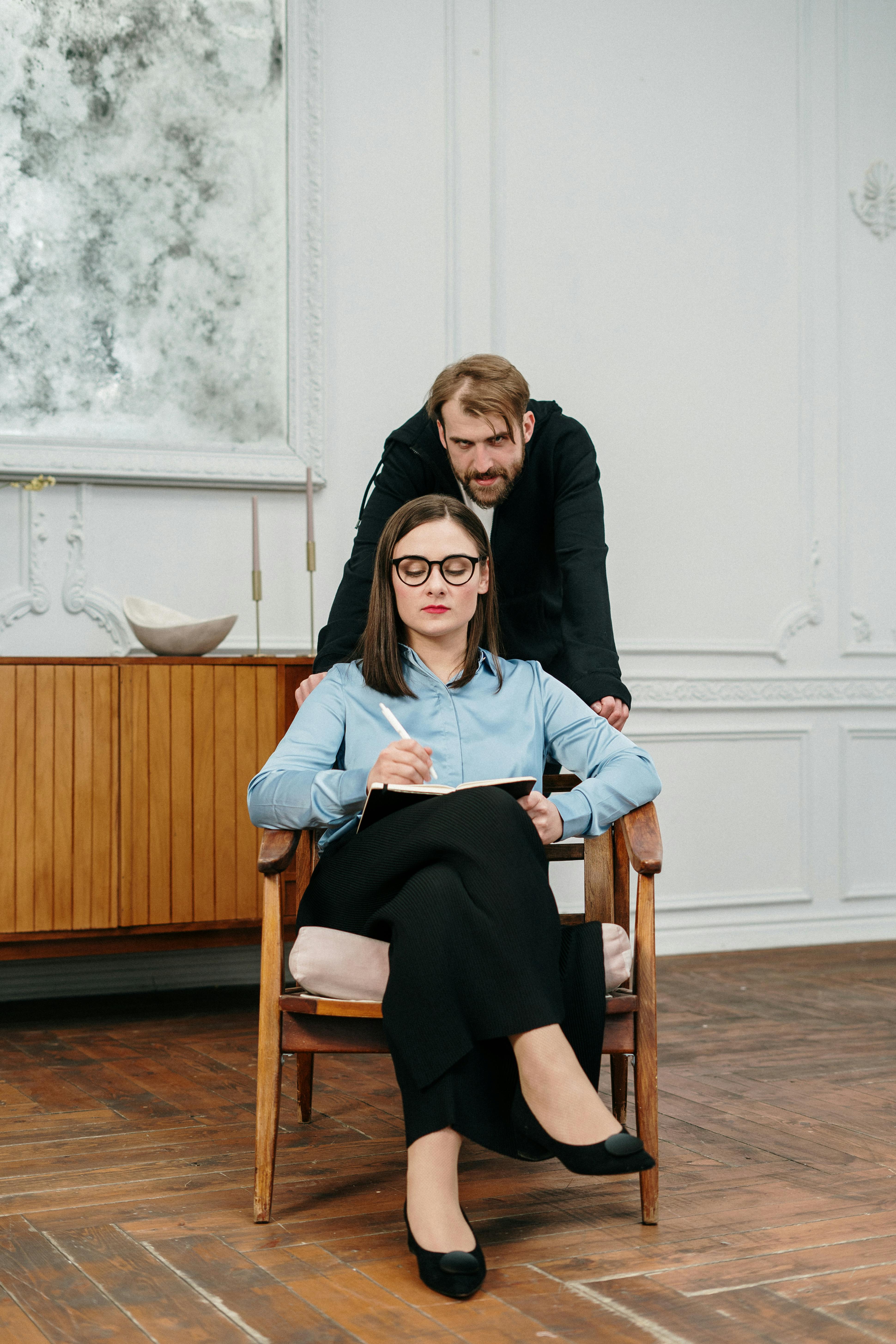 woman in black long sleeve shirt sitting on brown wooden armchair