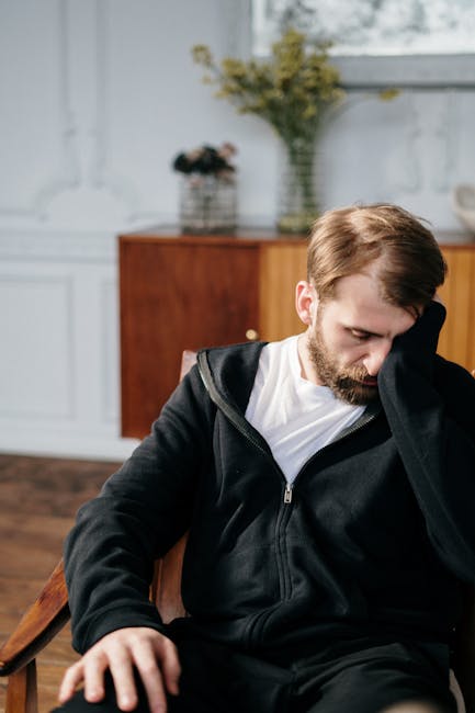 Man in Black Zip Up Jacket Sitting on Chair