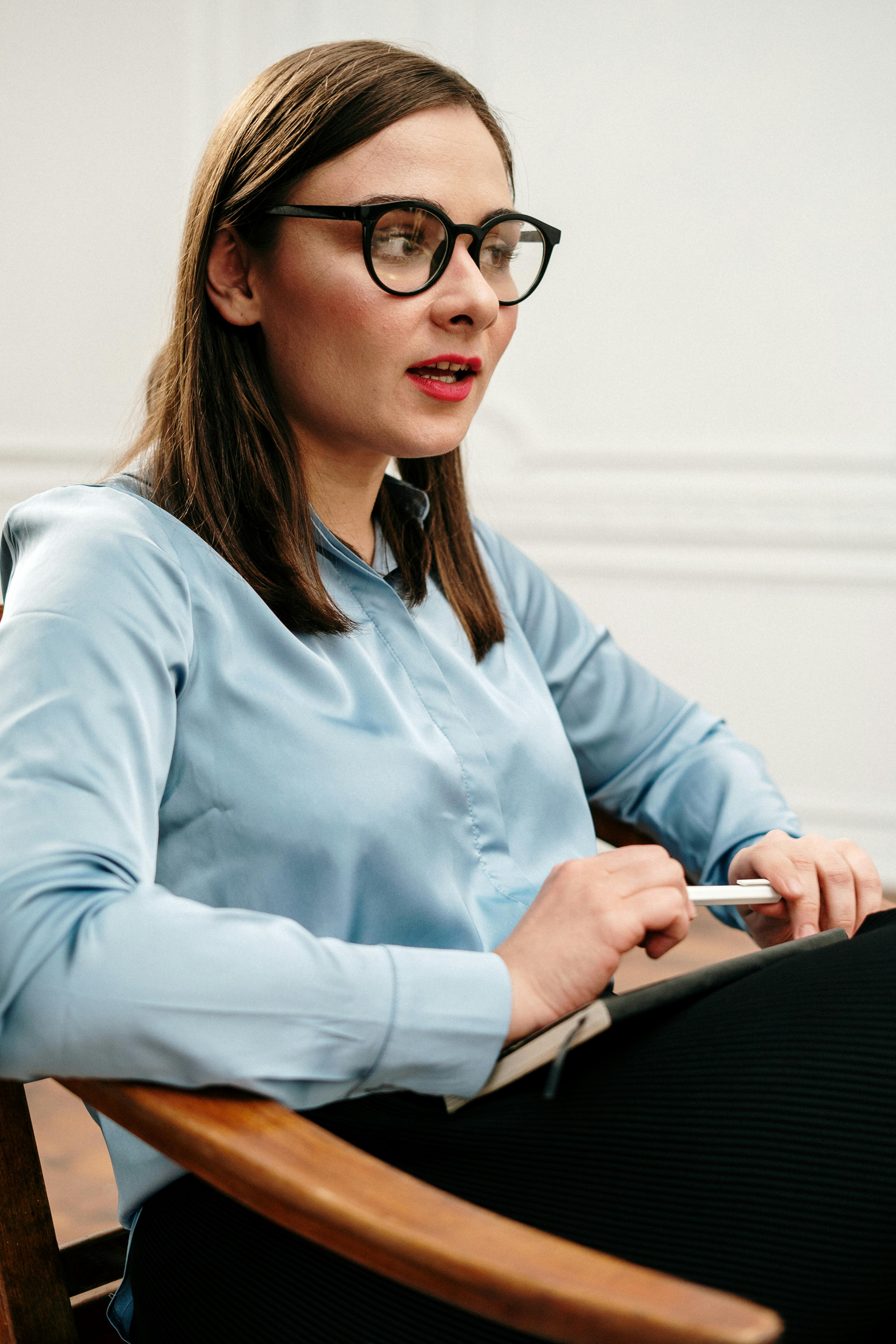 woman in blue dress shirt wearing black framed eyeglasses