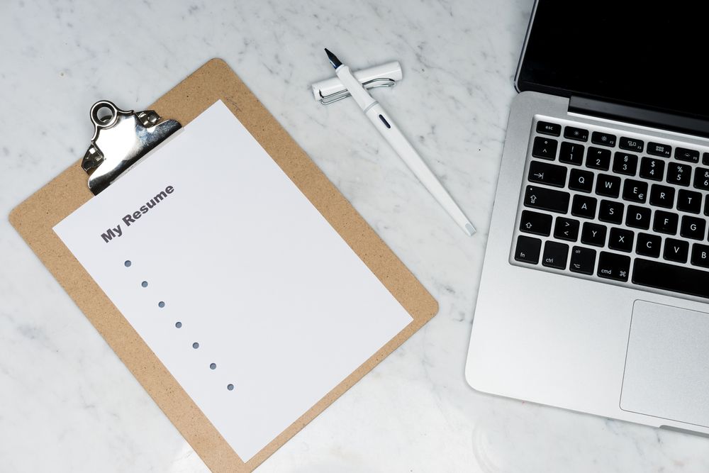 Curriculum vitae sur un porte-documents pres d'un ordinateur portable