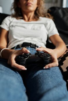 A woman enjoys gaming at home with a wireless controller, embodying relaxation and leisure.