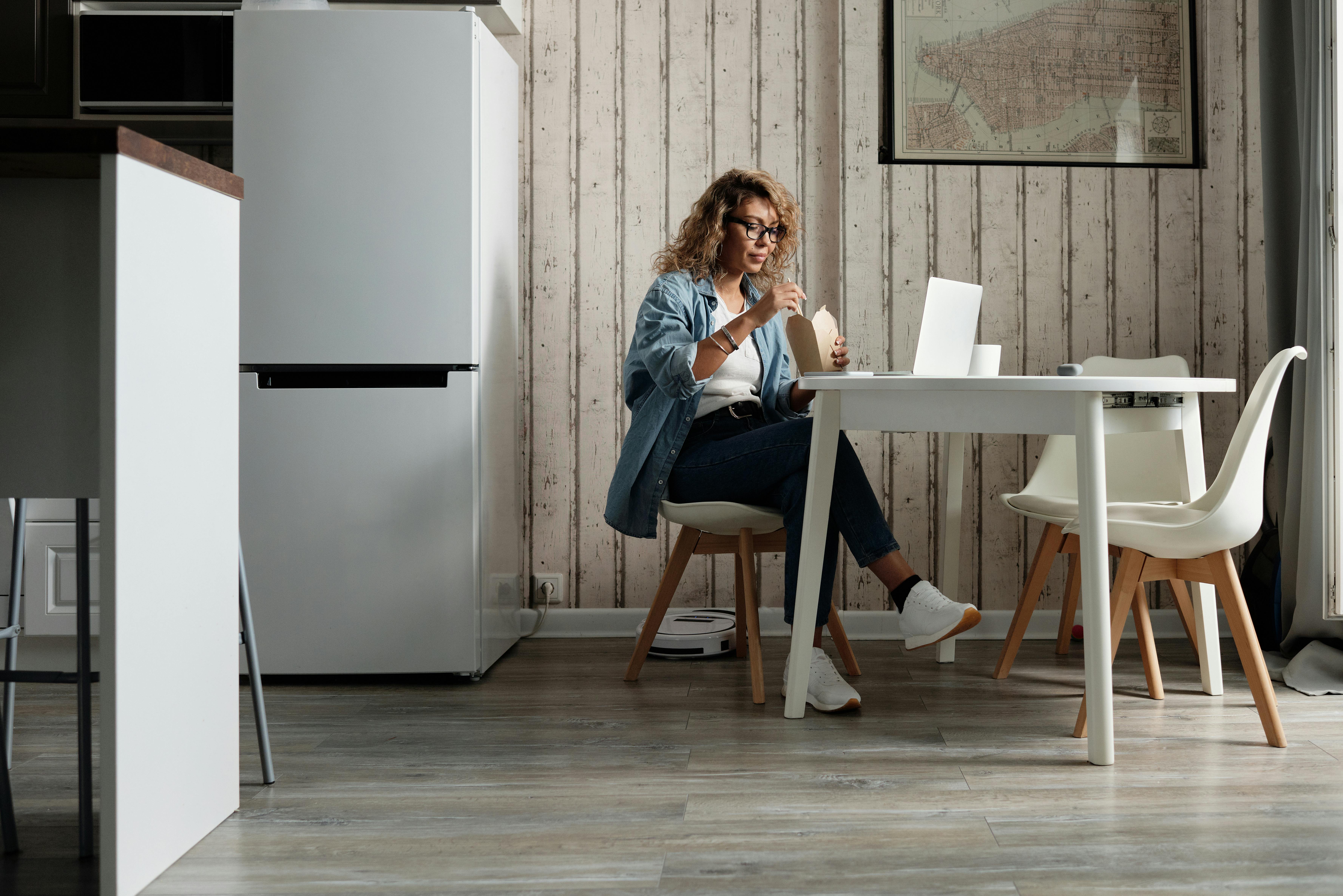 Hispanic woman comparing insurance quotes on laptop at kitchen table with Texas map visible