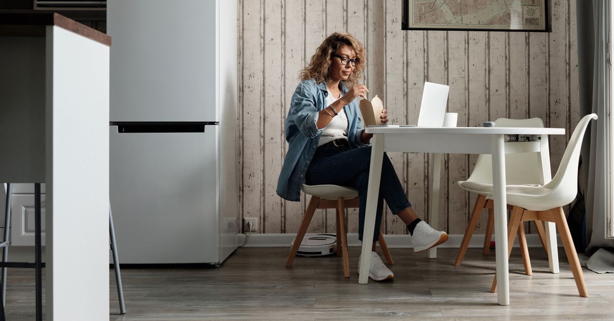 Hispanic woman comparing insurance quotes on laptop at kitchen table with Texas map visible