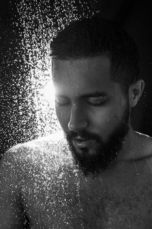Grayscale Photo of a Bearded Man Taking Shower