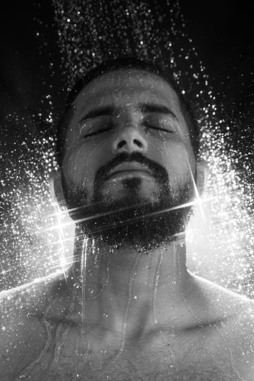 Grayscale Photo of a Bearded Man Taking Shower